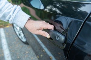 Closeup of hands on handle of car door